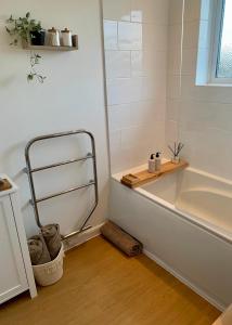 a bathroom with a bath tub with a shelf next to it at Central, Cosy & Stylish Home with Large Garden, Bournemouth in Bournemouth