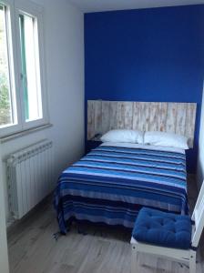 1 dormitorio con 1 cama con pared azul en I colori del mare, en Villaggio del Pescatore