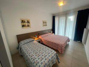 a hotel room with two beds and a window at Villa Marina Apartments - Agenzia Cocal in Caorle