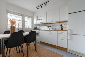 eine Küche mit weißen Schränken und einem Tisch und Stühlen in der Unterkunft Simple studio in trendy Södermalm - construction work in Stockholm