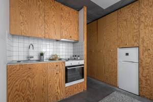 a kitchen with wooden cabinets and a white refrigerator at Comfy Studio easy to commute in Stockholm