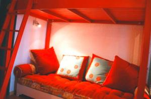 a red couch with four pillows on a bed at Appartement- Villard de Lans-8 pers in Villard-de-Lans