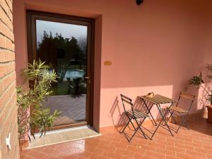 d'une terrasse avec des chaises et une table à côté d'une porte. dans l'établissement Agriturismo Podere Cirene, à Rispescia