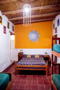 1 dormitorio con cama y pared amarilla en Apapacho Hostel en Tilcara
