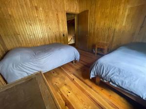 two beds in a room with wooden floors and wooden walls at Encantadora Cabaña del Lago - Parque La Pirámide 