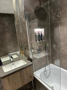 a bathroom with a shower and a sink and a tub at Richardson Deluxe Apartments - 3 Bed in London