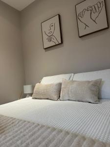 a bedroom with a white bed with two pictures on the wall at Richardson Deluxe Apartments - 3 Bed in London