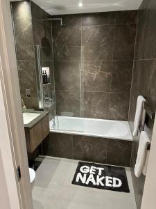 a bathroom with a tub and a get wanted sign on the floor at Richardson Deluxe Apartments - 3 Bed in London