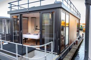 a small house on a boat in the water at Luxurious waterloft near beach and centre in Zeewolde