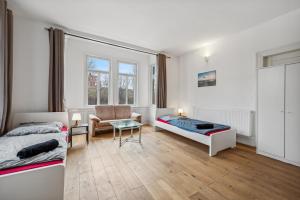 a bedroom with two beds and a couch and a chair at home2stay worker Apartments Metzingen in Metzingen