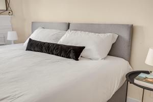 białe łóżko z czarną poduszką w obiekcie The Covent Courtyard Flat w Londynie