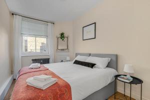 een slaapkamer met een bed met witte lakens en een raam bij The Covent Courtyard Flat in Londen