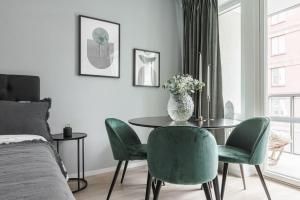 ein Schlafzimmer mit einem Tisch, grünen Stühlen und einem Bett in der Unterkunft Beautiful and cozy Studio in a New building in Stockholm