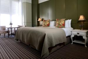 a bedroom with a large bed with green walls and a table at The Southern Belle in Brighton & Hove