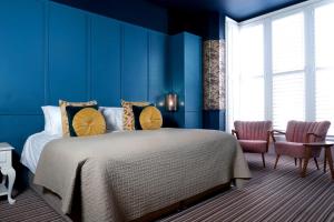 a blue bedroom with a bed and two chairs at The Southern Belle in Brighton & Hove