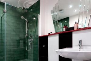a bathroom with a sink and a shower with green tiles at The Southern Belle in Brighton & Hove