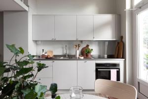 a kitchen with white cabinets and a table at Explore Gothenburg from modern apt for 4 guest in Gothenburg