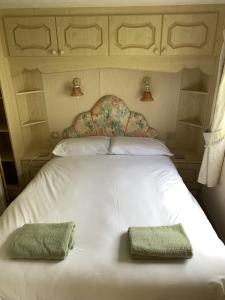 a white bed with two green towels on it at Osprey Caravan in Onich