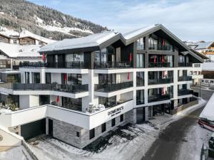 un edificio de apartamentos con una montaña cubierta de nieve en el fondo en Domenigs Luxury Apartments, en Fiss