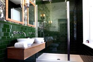 a green tiled bathroom with two sinks and a shower at The Southern Belle in Brighton & Hove