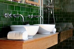 uma casa de banho com dois lavatórios num balcão com azulejos verdes em The Southern Belle em Brighton & Hove