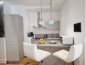 a kitchen with two white chairs and a microwave at HomeHoliday LUXE - MY PLACE SANREMO in Sanremo