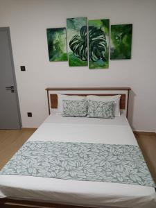 een slaapkamer met een bed met vier schilderijen aan de muur bij J&J in Centre de Flacq
