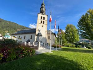 uma igreja com uma torre com bandeiras na relva em un nid avec balcon em Saint-Gervais-les-Bains