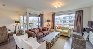 a living room with a couch and a table and chairs at La Cabane Penthouse in Nieuwvliet-Bad