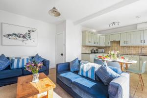 a living room with a blue couch and a table at UpperDeck, Salcombe (Free Parking) in Salcombe
