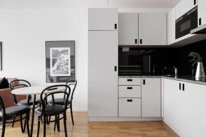 uma cozinha com armários brancos e uma mesa com cadeiras em Modern City Retreat w. workspace em Kottla