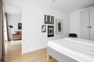 KottlaにあるModern City Retreat w. workspaceの白いベッドルーム(ベッド1台付)が備わります。壁には絵画が飾られています。