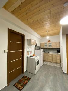 Il comprend une cuisine avec des appareils blancs et un plafond en bois. dans l'établissement D&M STUDIO ΡΙΟ ΠΑΤΡΑ, à Patras