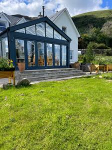 a house with a large glassconservatory on a lawn at Clachan Garden B&B in Garve