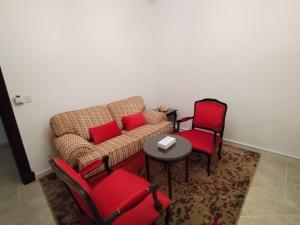 uma sala de estar com um sofá e cadeiras vermelhas em فندق روتانة الفرسان بالحمرا em Jeddah