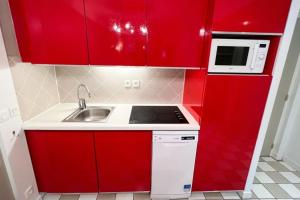 una pequeña cocina con armarios rojos y fregadero en 6-person apartment with swimming pool tennis court and free parking REF25 en Le Touquet-Paris-Plage