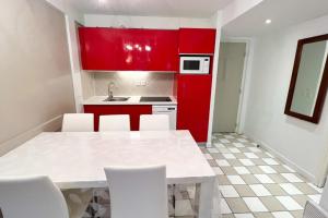 una cocina con armarios rojos y una mesa y sillas blancas. en 6-person apartment with swimming pool tennis court and free parking REF25 en Le Touquet-Paris-Plage