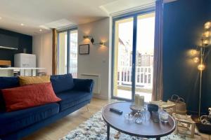 a living room with a blue couch and a table at Cosy flat close to the sea with large terrace in Le Touquet-Paris-Plage