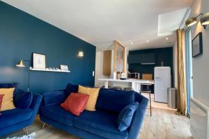 a living room with a blue couch and a kitchen at Cosy flat close to the sea with large terrace in Le Touquet-Paris-Plage