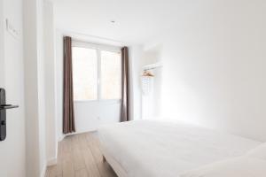 ein weißes Schlafzimmer mit einem Bett und einem Fenster in der Unterkunft Central Apartment in the heart of the Marais in Paris