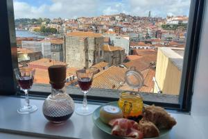 ein Tisch mit zwei Weingläsern und einem Teller mit Essen in der Unterkunft MyRiverPlace N 4 Private Terrace River View Porto apartments in Vila Nova de Gaia + 34 Fotos