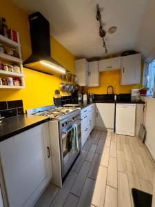 a kitchen with white cabinets and a stove top oven at Ben & Maria's Guesthouse in Bath