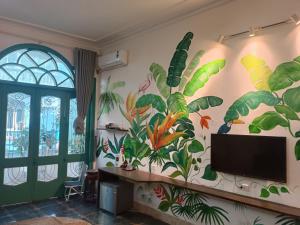 a living room with a mural of plants on the wall at Nemohousehomestay in Hanoi