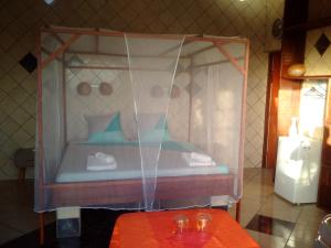 a canopy bed in a room with a table at Villa Pistaches in Grand-Bourg