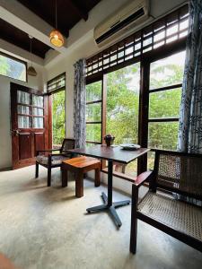 - un salon avec une table, des chaises et des fenêtres dans l'établissement Milkyway Holiday Resort, à Unawatuna