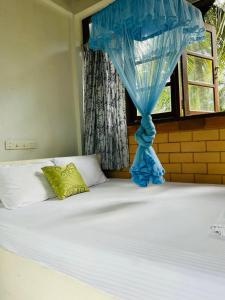 a bed with a blue curtain and a window at Milkyway Holiday Resort in Unawatuna