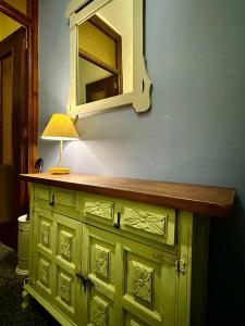 a green cabinet with a mirror and a lamp on it at Apartamento Royal Centro de Ronda in Ronda