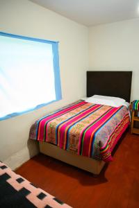 Un dormitorio con una cama con una manta de colores. en Quinuawasi House, en Ocosuyo