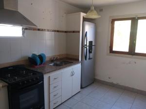 a kitchen with a stove and a refrigerator and a sink at Casa 3 ambientes para 6 personas céntrica in Miramar +16 photos