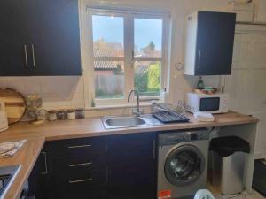een keuken met een wastafel en een wasmachine bij 2 Bedroom Cosy Cottage 